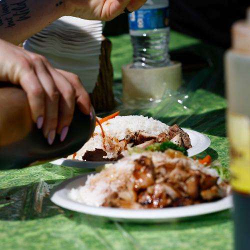 hand pouring sauce onto rice and chicken