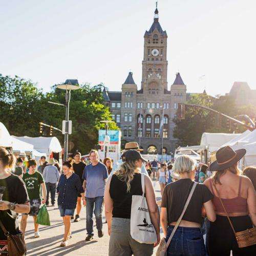 crowd of people perusing art's fest tents by city hall
