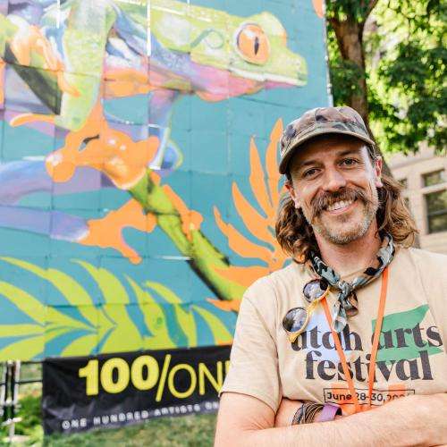 artist in front of finished 100/One mural