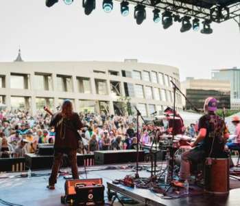 Blonde woman playing guitar with band members in the background Blonde woman playing guitar with band members in the background